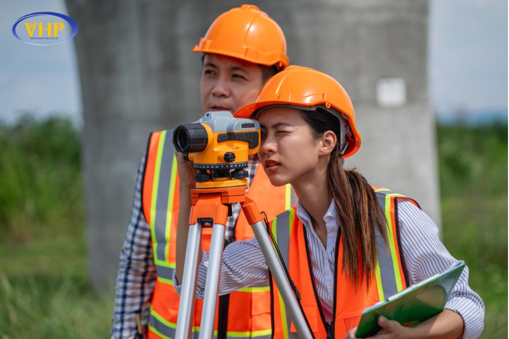 kỹ sư đang sử dụng máy thủy bình tại công trường xây dựng